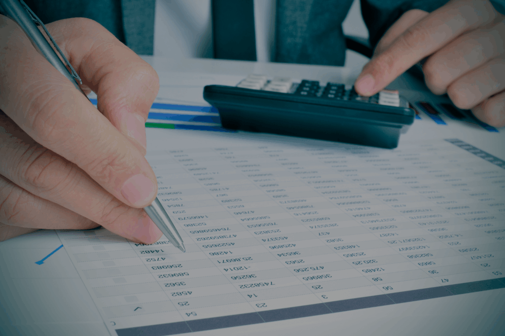 Manos de asesor revisando hoja de cálculo con calculadora, concepto de asesoría fiscal y planificación tributaria.